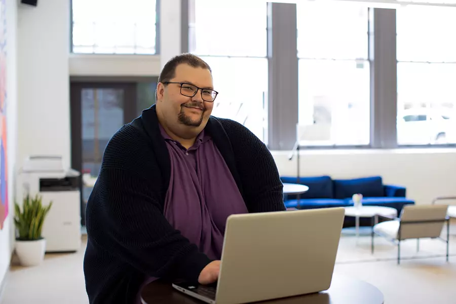 A man smiles while using a laptop