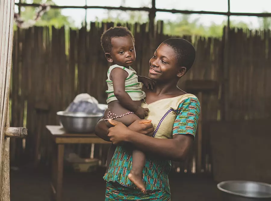 A smiling women holds a small child in her arms