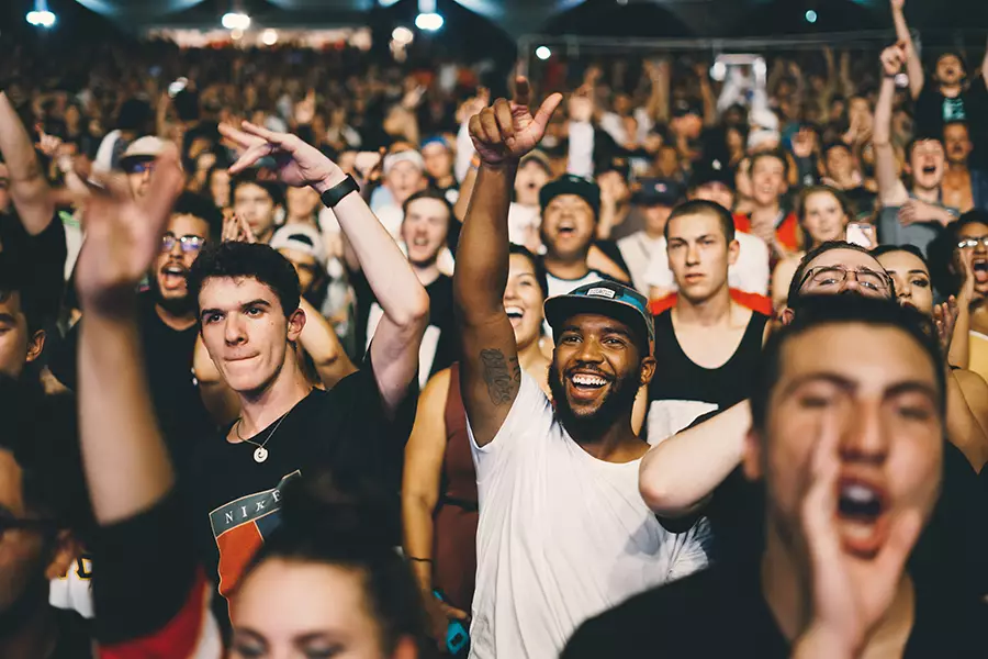 A crowd of young people cheer at a concert