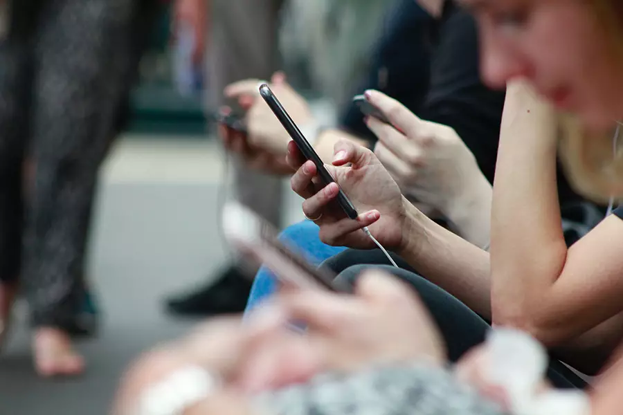 A group of people in a park look at their cellphones